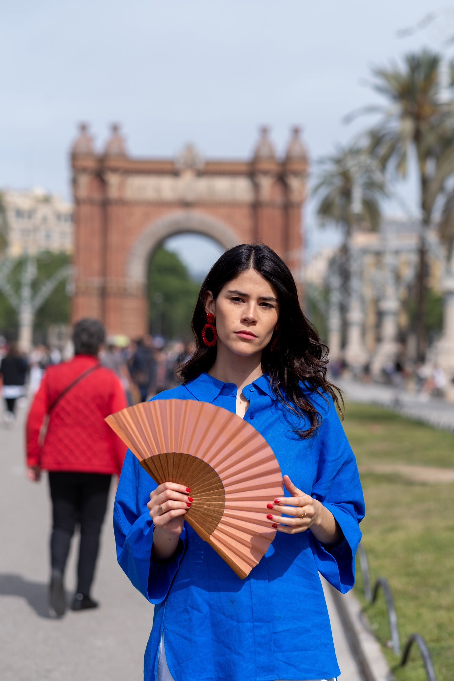 Mujer utilizando abanico color rosa coral en el arco del triunfo de Barcelona