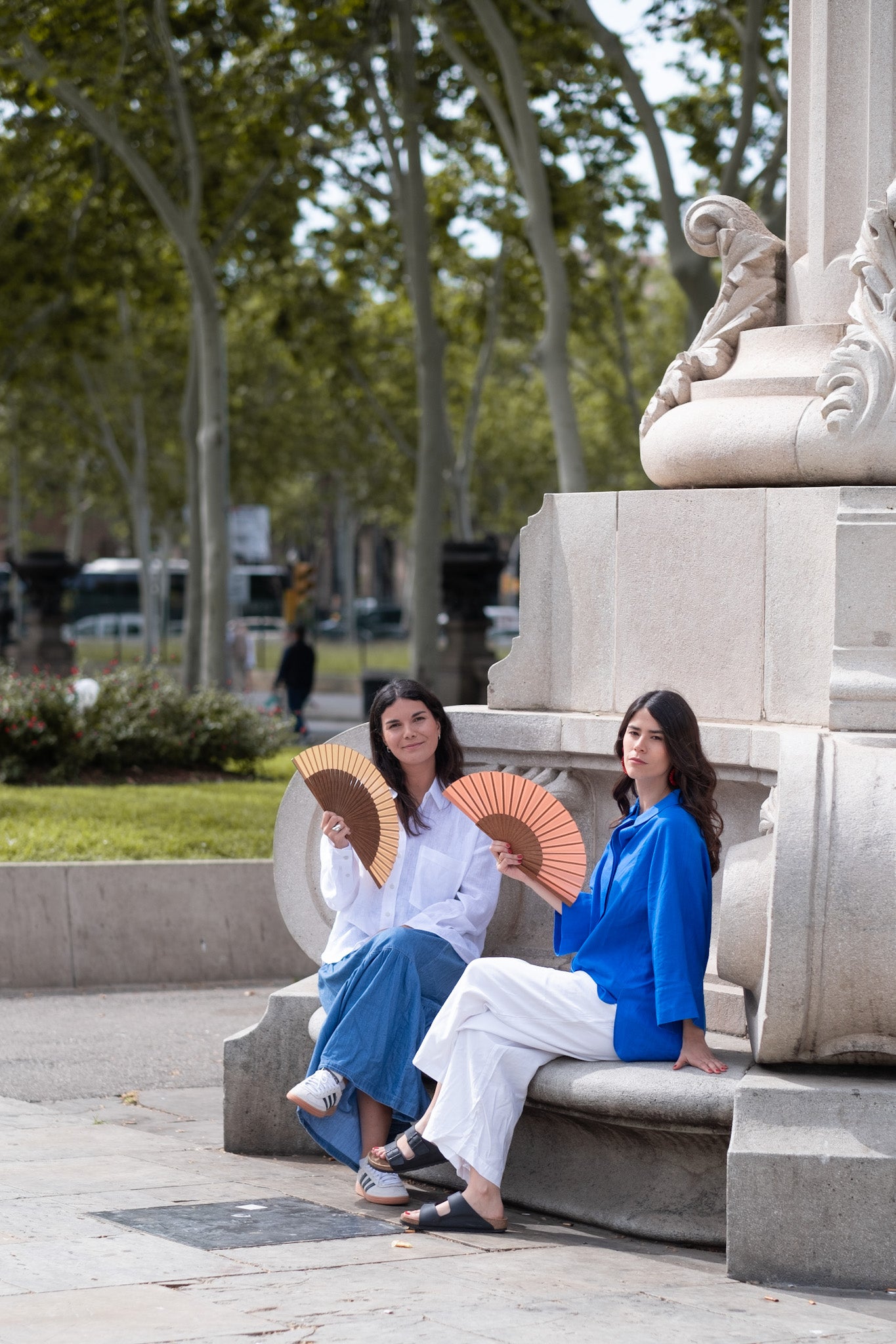 Dos mujeres vistiendo abanicos camel y rosa en el paseo del arco del triunfo de barcelona