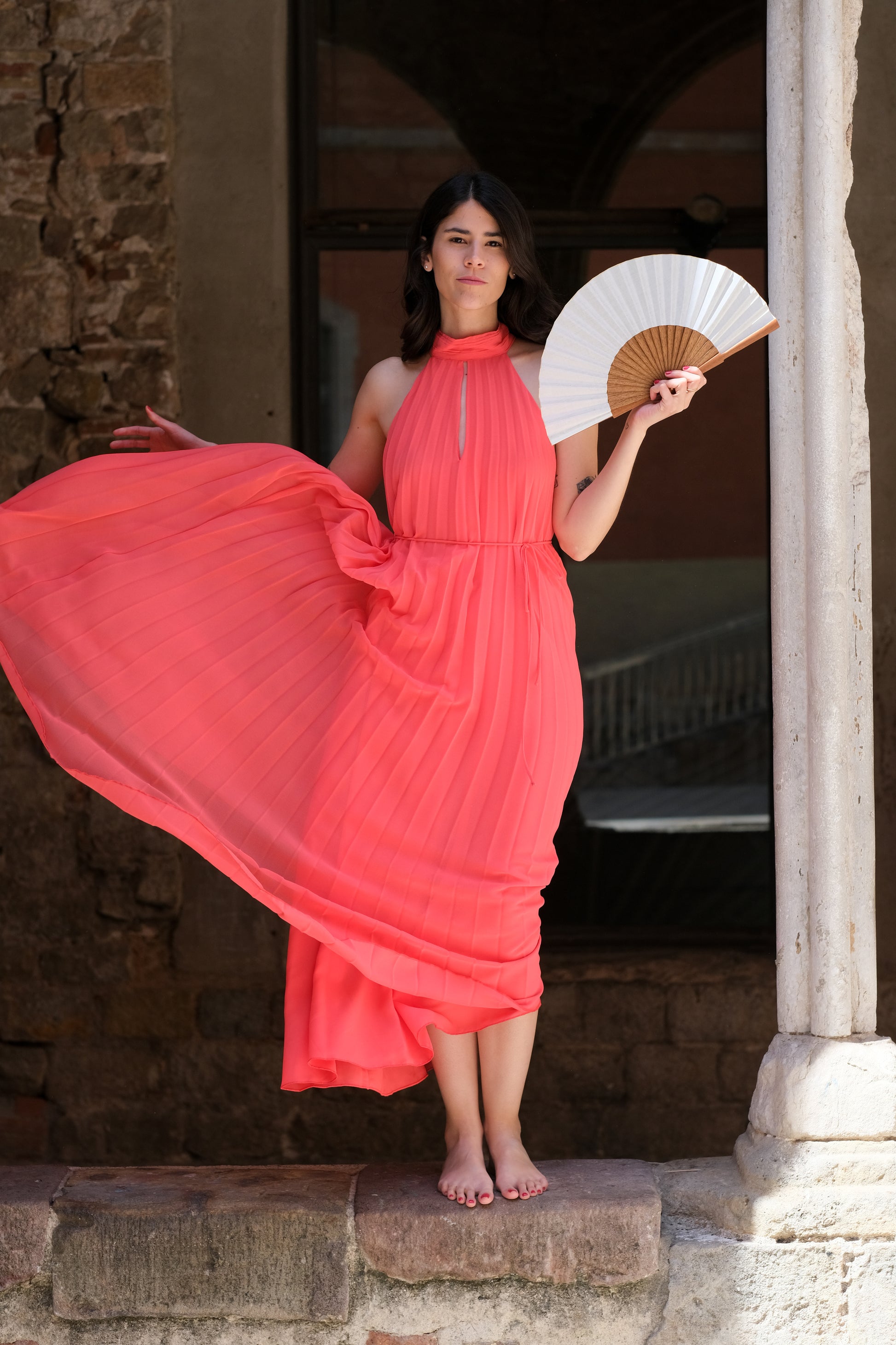 Mujer utilizando abanico color blanco y vestido fucsia en Barcelona. Marca rafega. 